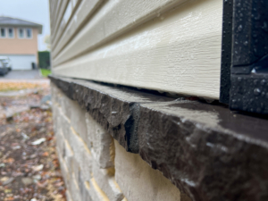 Exterior water management defect found during a New Construction Home Inspection in Jersey—missing flashing and improperly sloped stone veneer in Whippany.