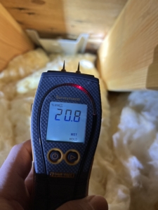 A professional moisture meter confirming active moisture intrusion in attic framing, a critical part of our home inspection attic tips.