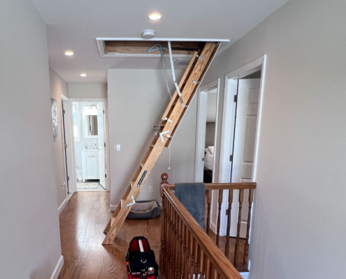 A professional home inspector using a pull-down ladder to provide home inspection attic tips in a North Jersey residence.